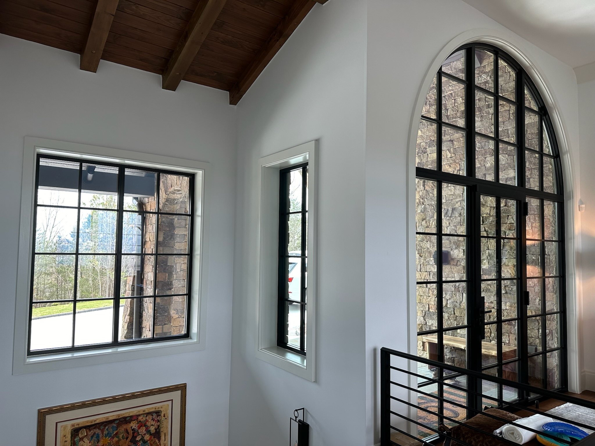 Arched and rectangular black-framed Westline windows along an upper hallway in a Lake Keowee, SC home