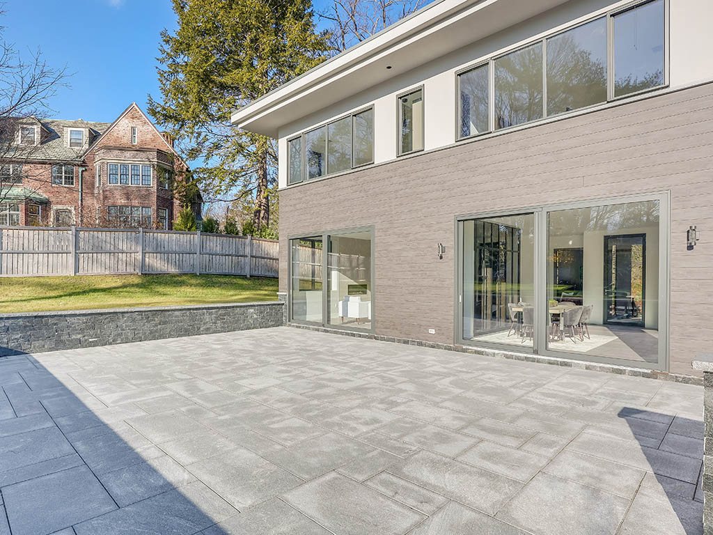 Stone terrace of a modern villa in Brookline, MA with Westline sliding glass doors and large upper-floor windows