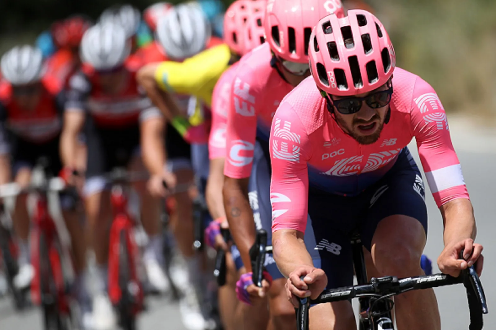 A USA Cycling rider in a pink jersey leading a pack of cyclists in a road race