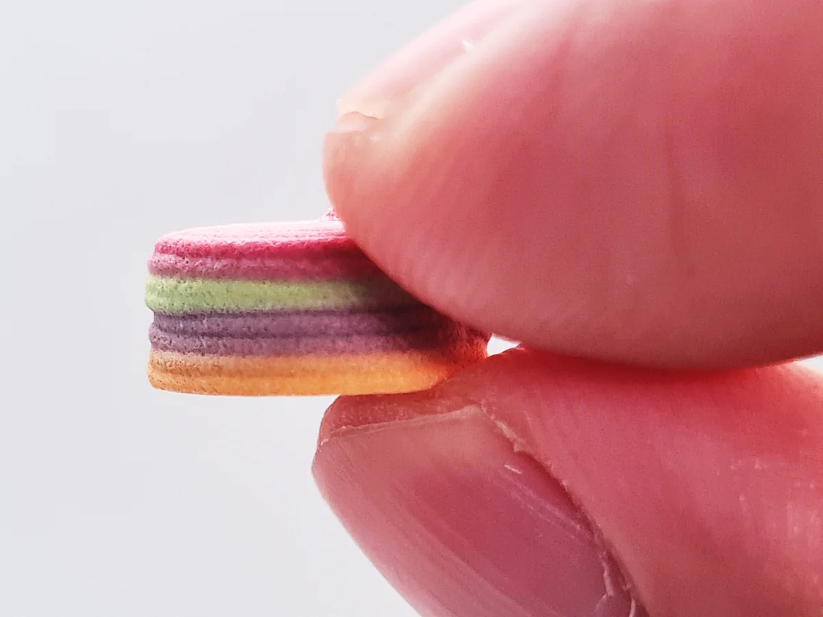 CraftTab 4-in-1 polypill, a multi-layer 3D-printed tablet, held between two fingers