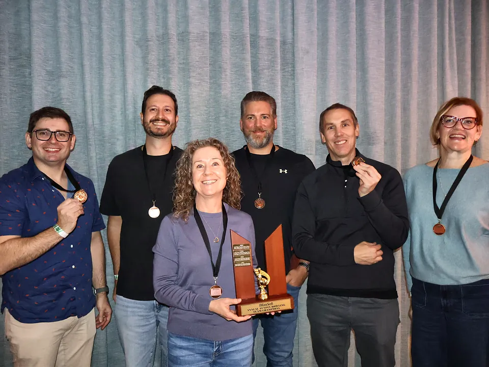 MaxSoft team members showing their medals and trophy