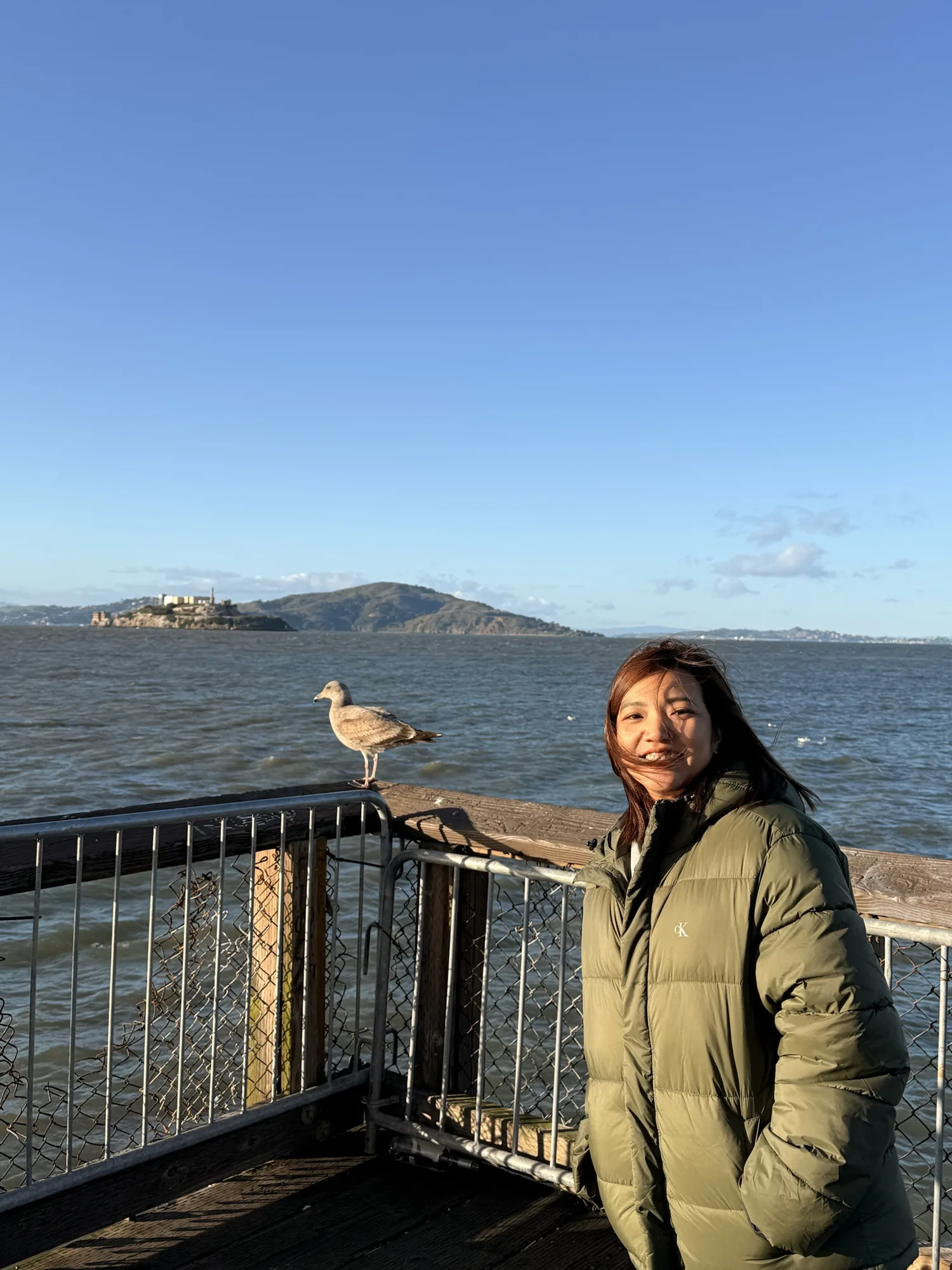 Aom smiling on a windy pier in San Francisco