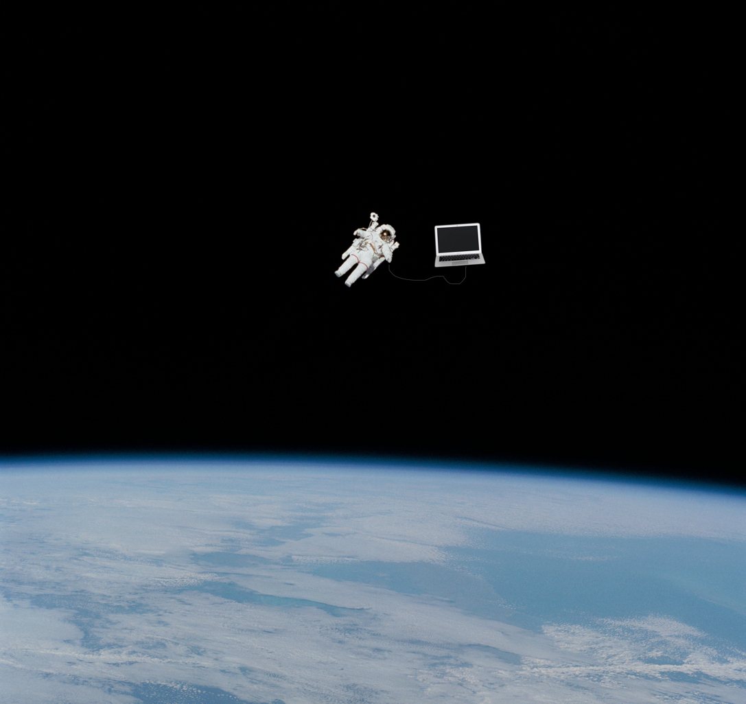 Astronaut floating above Earth, tethered by a cable to a floating laptop