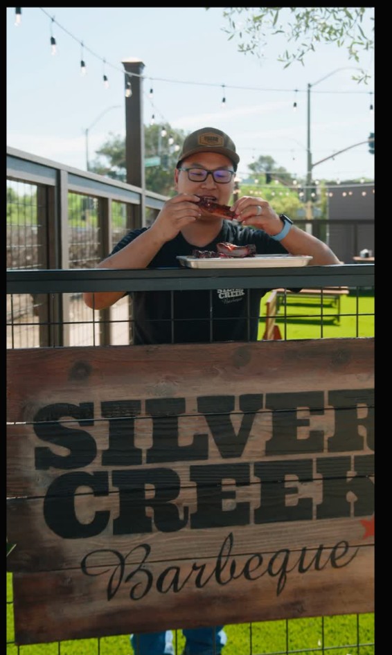 Guest enjoying BBQ behind a restaurant sign
