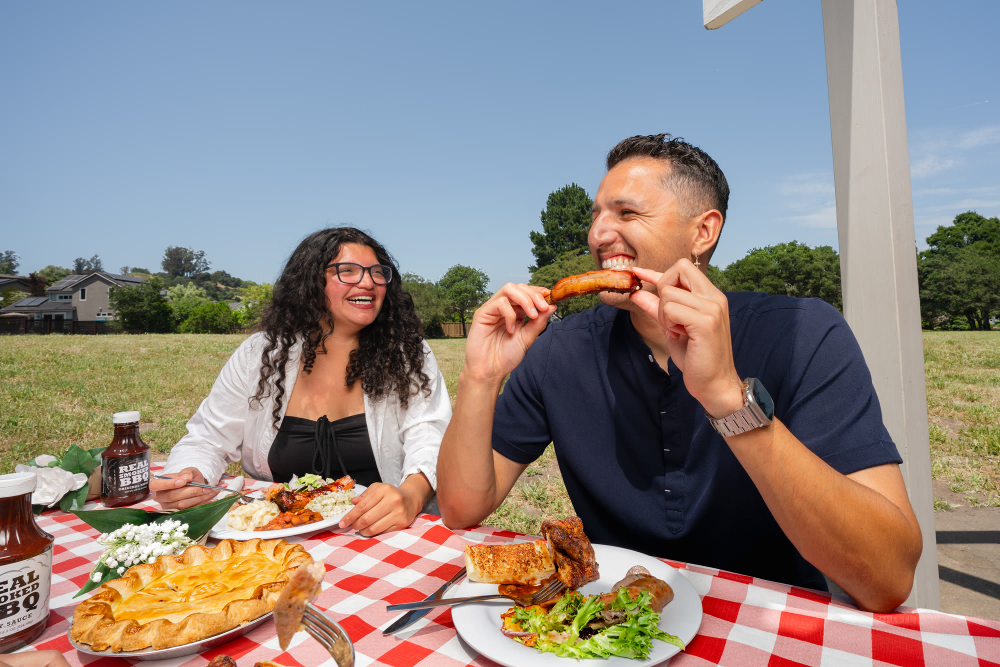 Guests enjoying smoked BBQ at an outdoor picnic table