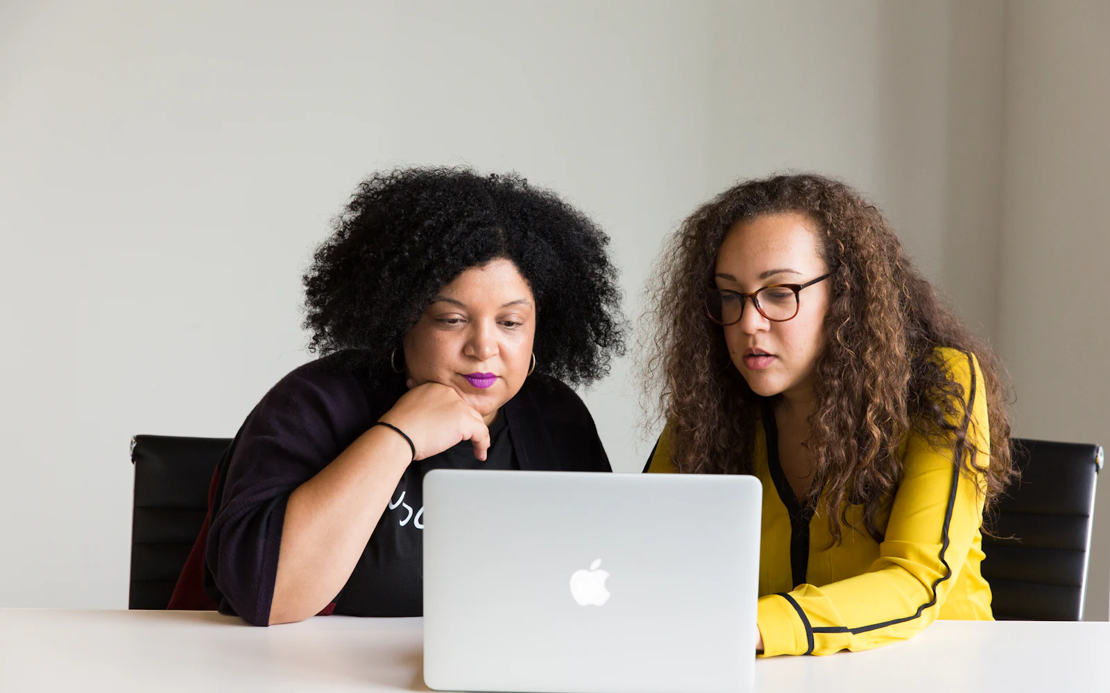 Two women sitting together and studying a laptop screen closely