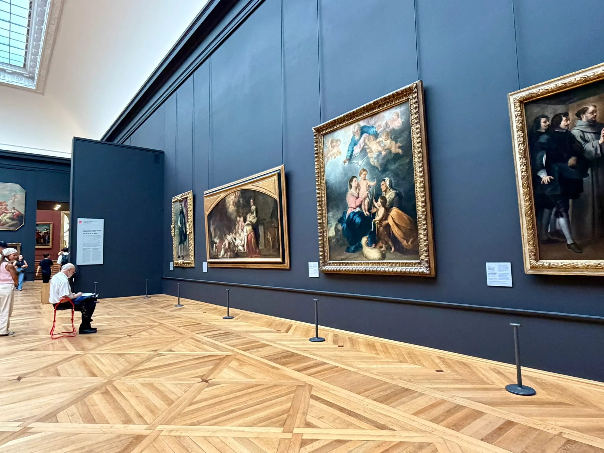 Spanish paintings in the Louvre galleries, with dark blue walls and gilded frames