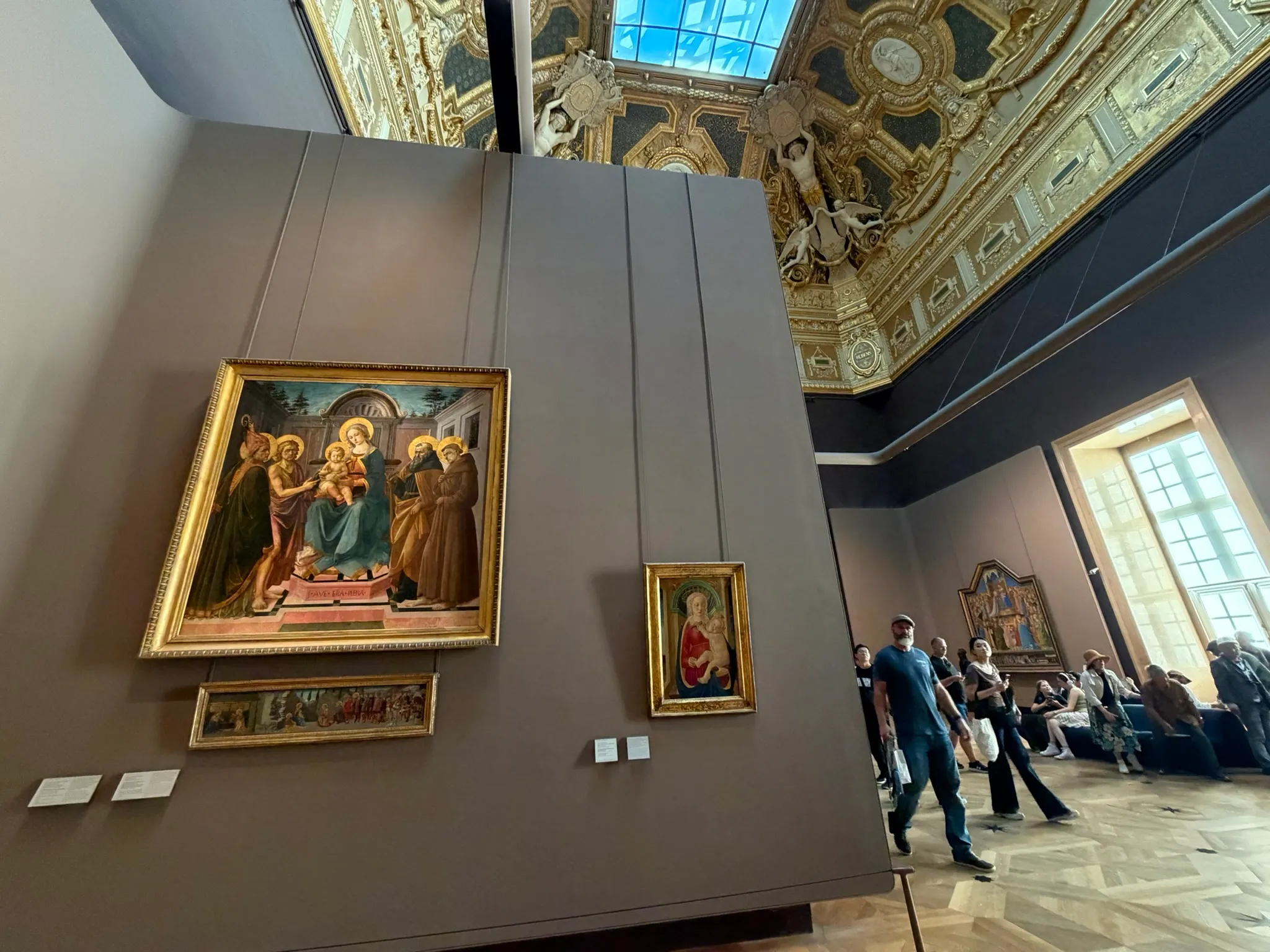 Italian Renaissance paintings displayed in the Louvre's Salon Carré beneath its decorated ceiling