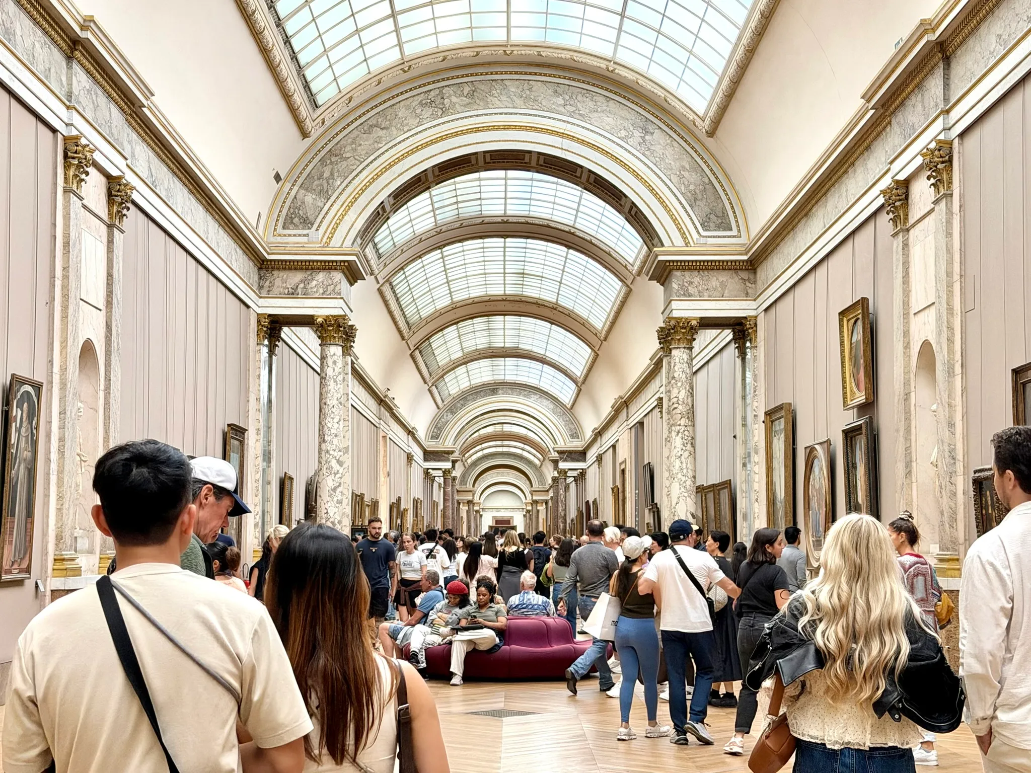 Paintings displayed along the Louvre's Grande Galerie beneath its vaulted glass ceiling