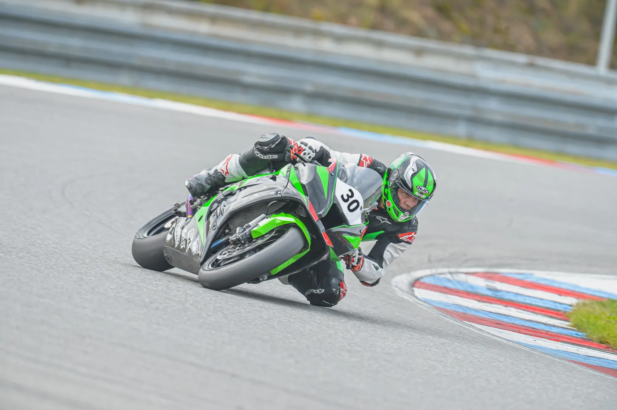 Fahrer auf grüner Kawasaki in Schräglage auf der Rennstrecke