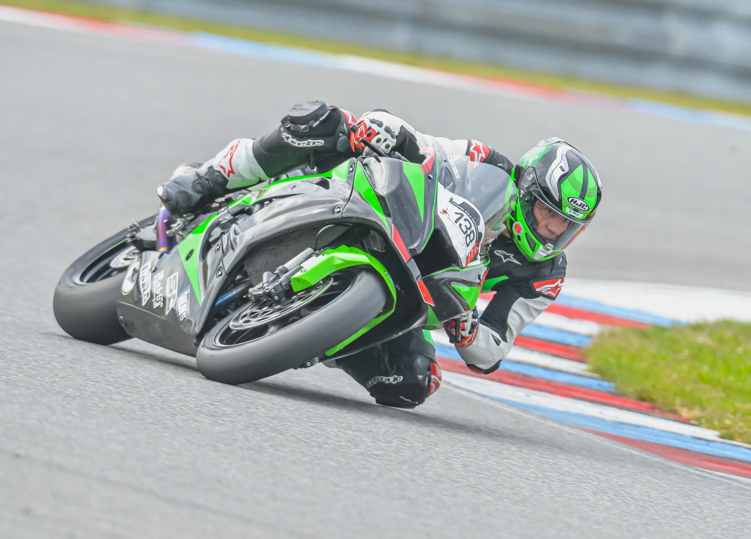 Fahrer auf grüner Kawasaki in Schräglage auf der Rennstrecke