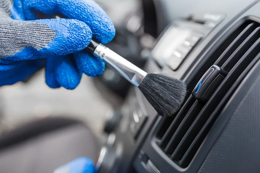 A detail brush removing dust from a vehicle air vent