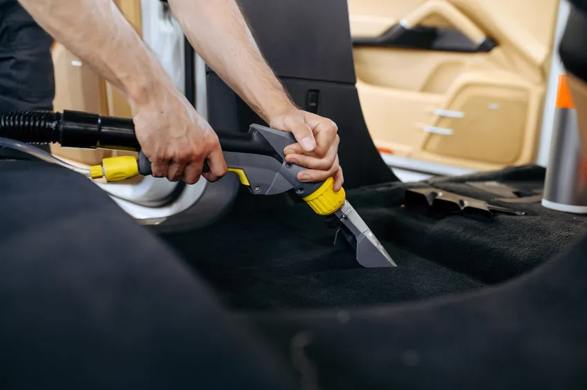 A wet extraction nozzle cleaning fabric carpet inside a vehicle