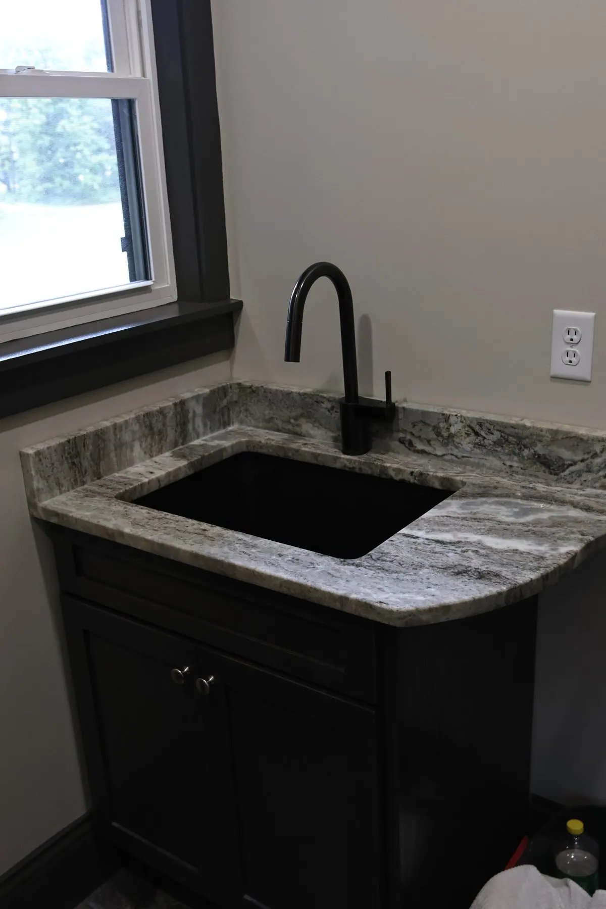 Black sink and faucet set into a stone countertop.