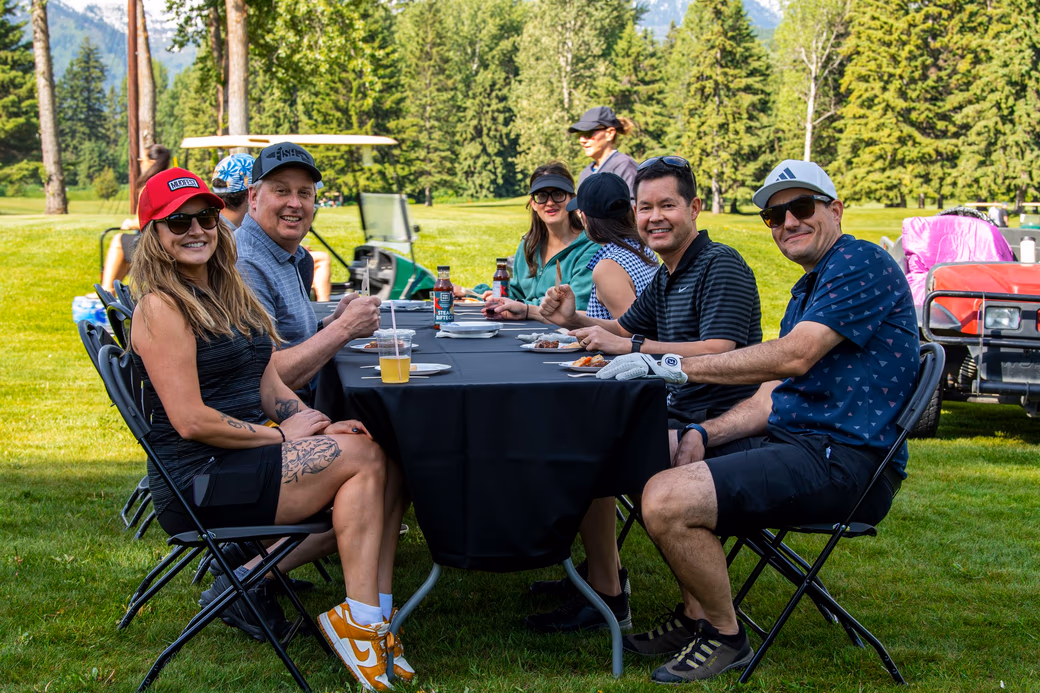 Players sharing drinks at an outdoor table between holes