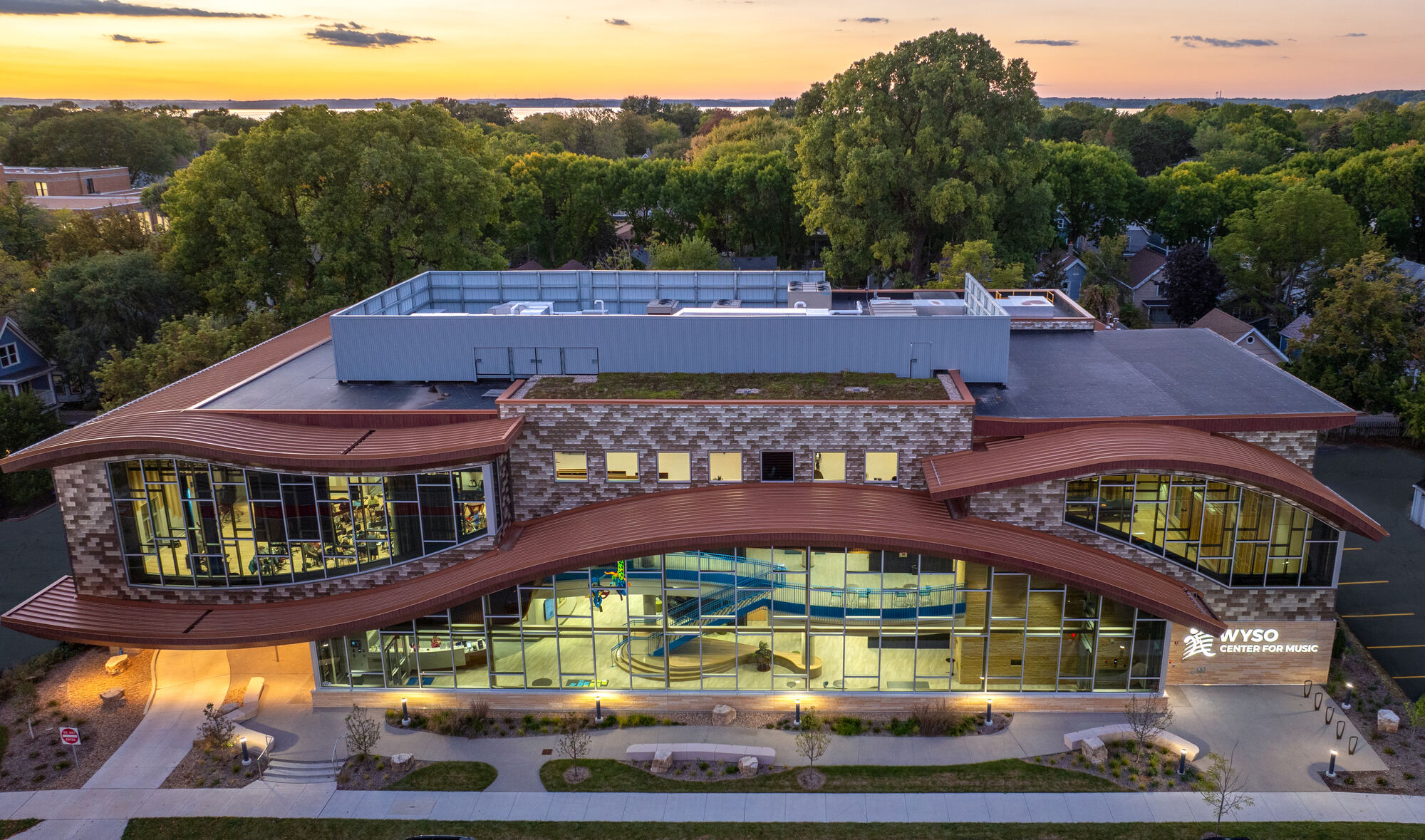 The WYSO Center at sunset, with its curved copper roofline and glass facade lit from within