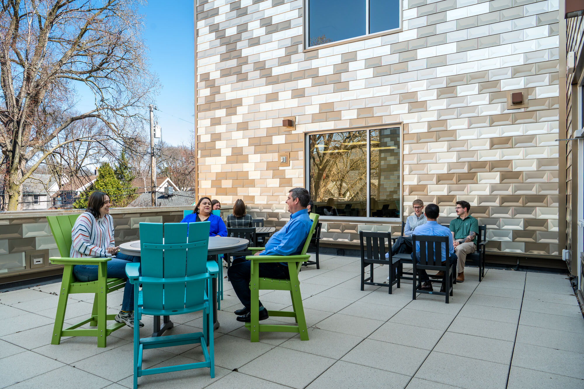 Colleagues talking around tables on the second-floor patio