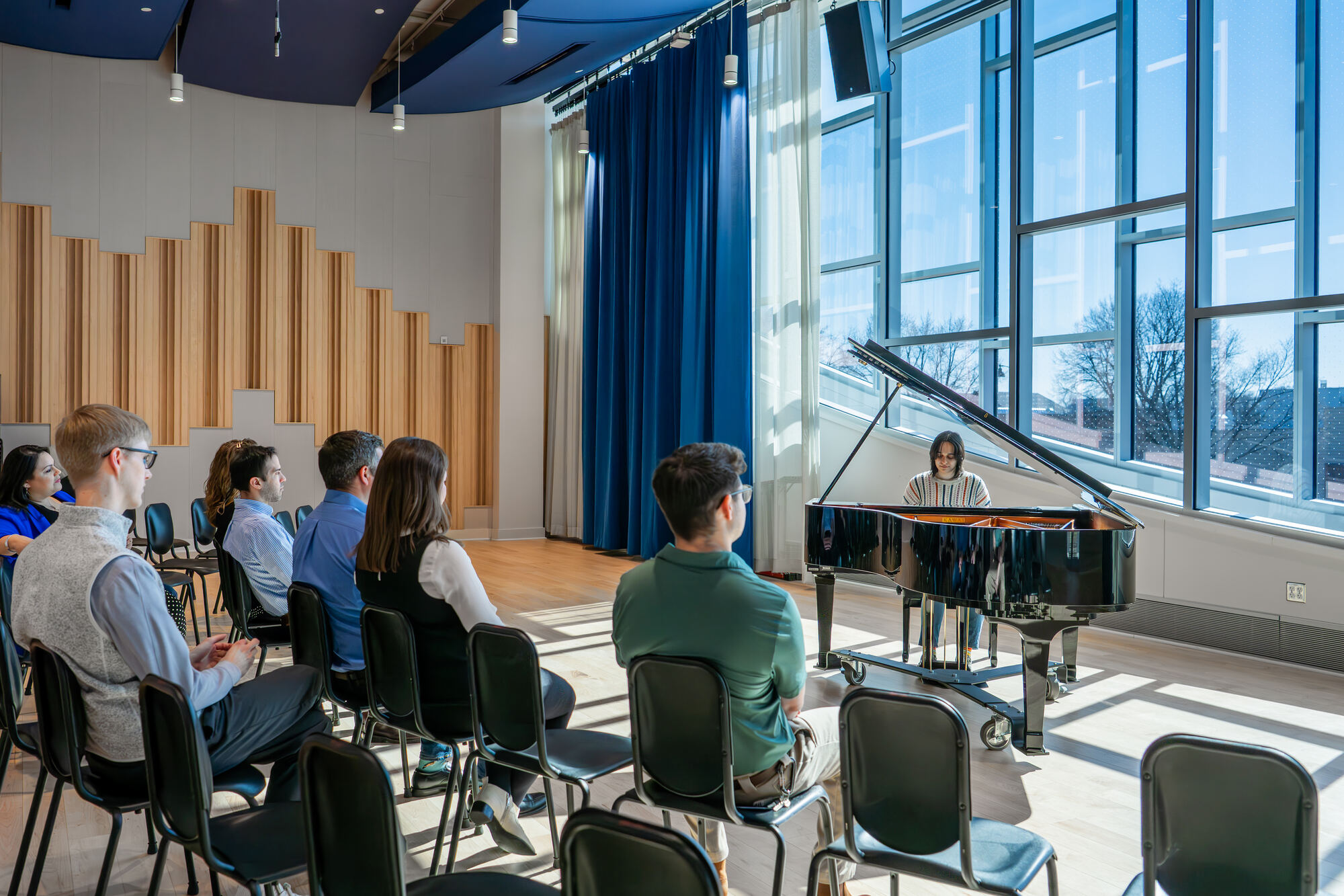 A young pianist performs for an audience in sunlit Founders Hall