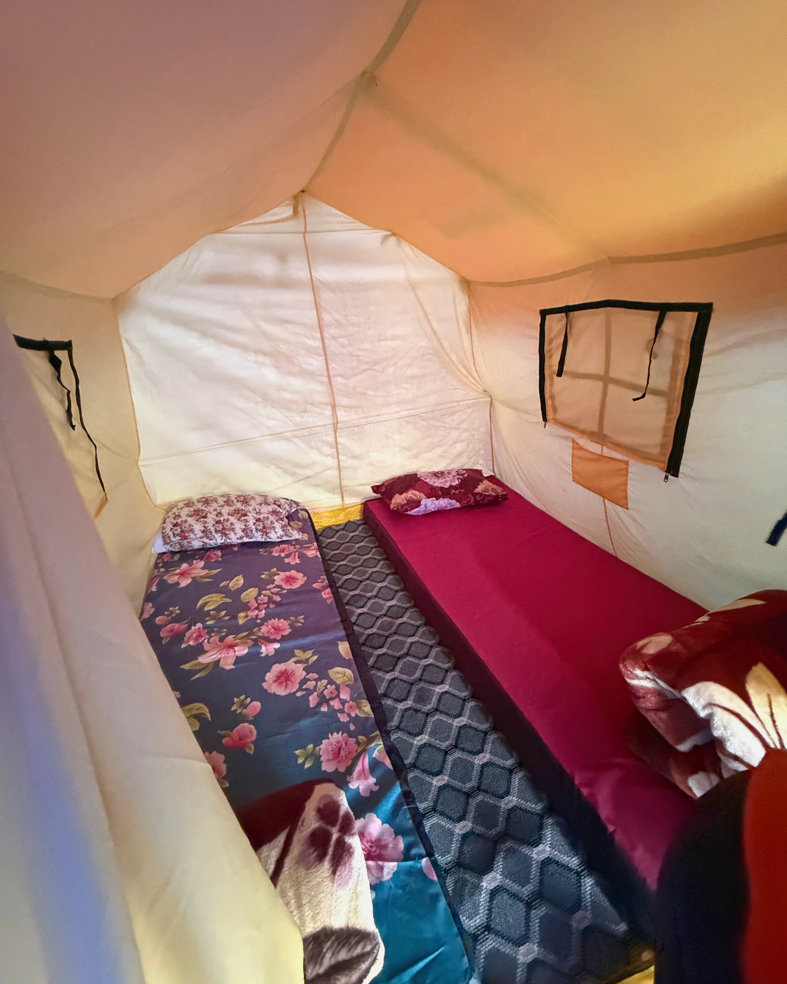 Two made-up single beds with pillows and blankets inside an Everest Base Camp expedition sleeping tent.