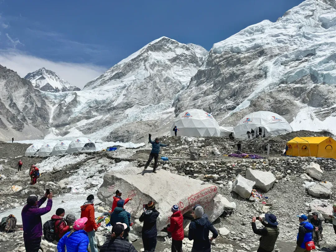 Snow-covered Himalayan mountains above expedition tents and trekkers at Everest Base Camp on the Khumbu Glacier.