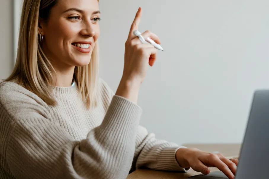 Happy client raising her hand while working on a laptop