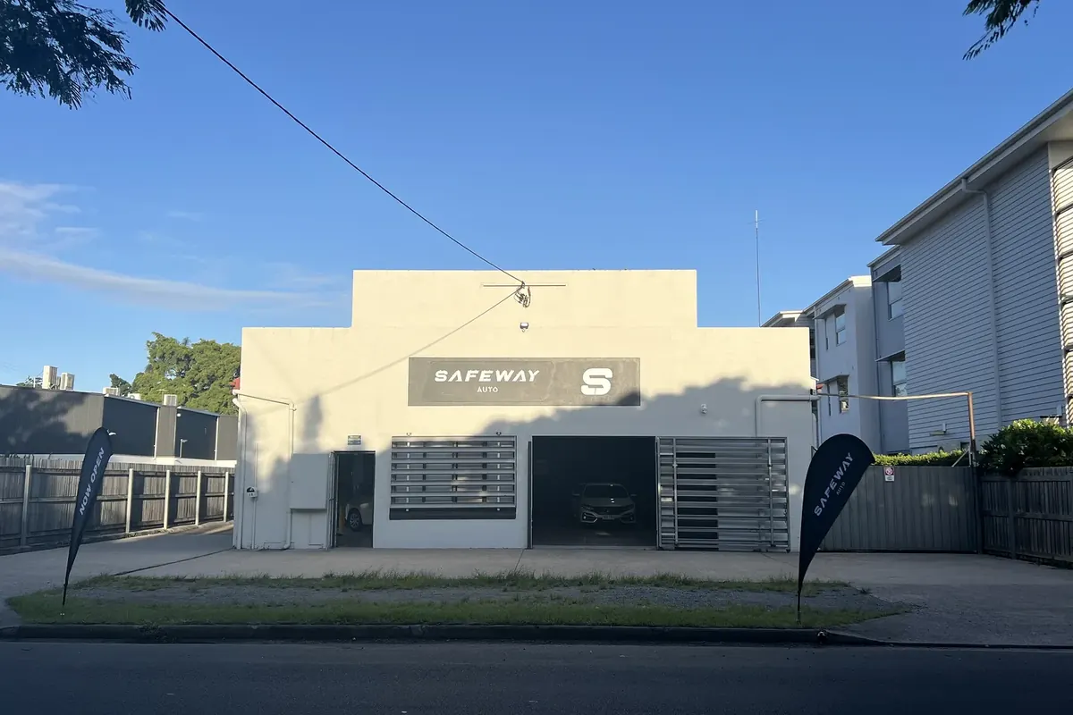 Safeway Auto’s first premises in Bulimba: a white building with the Safeway Auto sign and flags out front