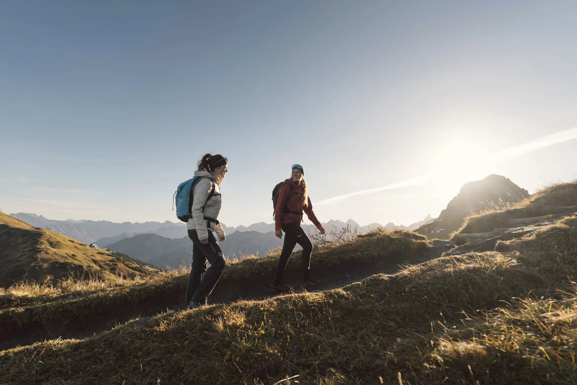 Zwei Wanderer im Gegenlicht auf einem Bergrücken im Herbst