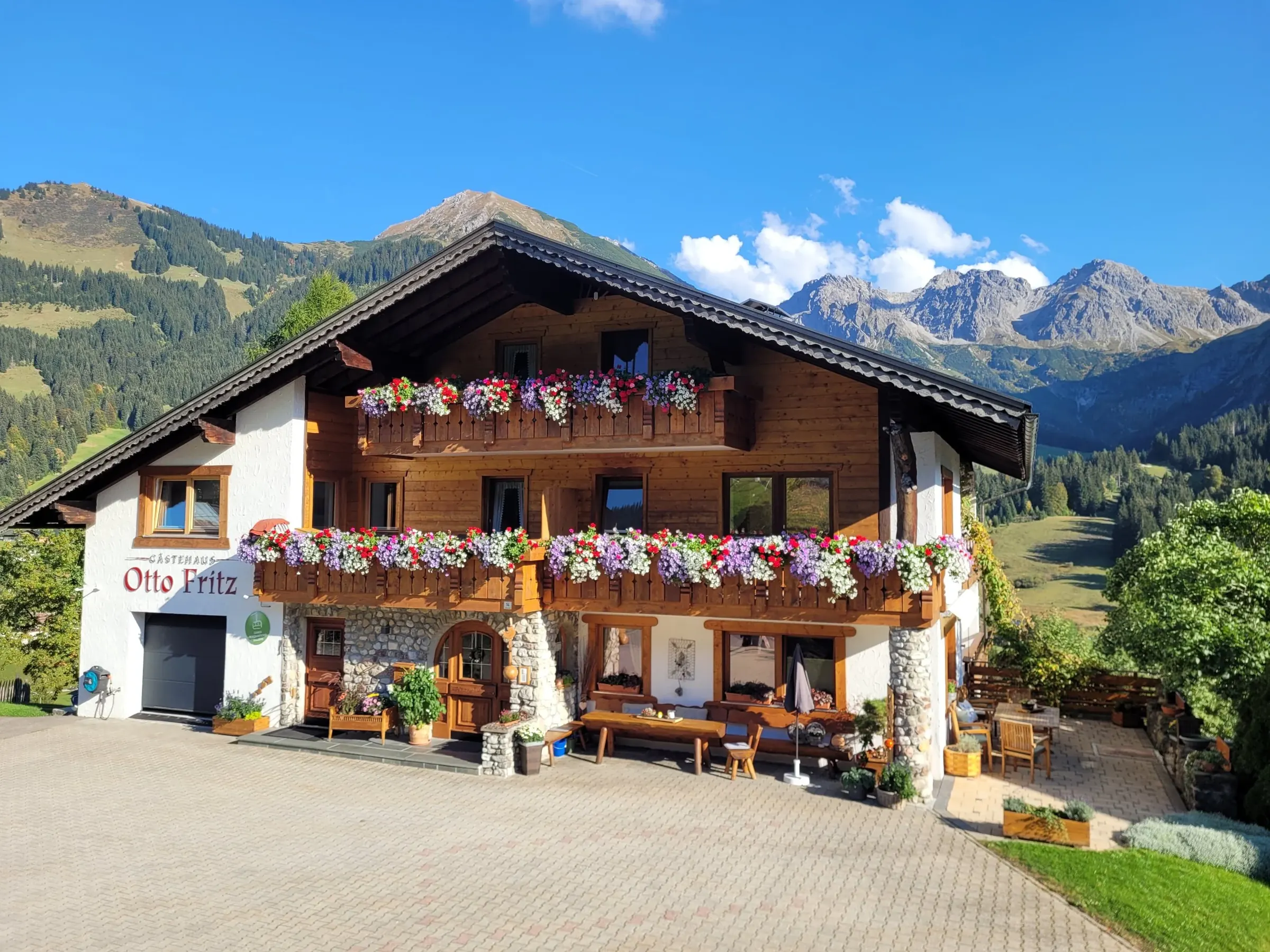 Gästehaus Otto Fritz mit Blumenbalkonen vor Bergkulisse in Mittelberg, Kleinwalsertal