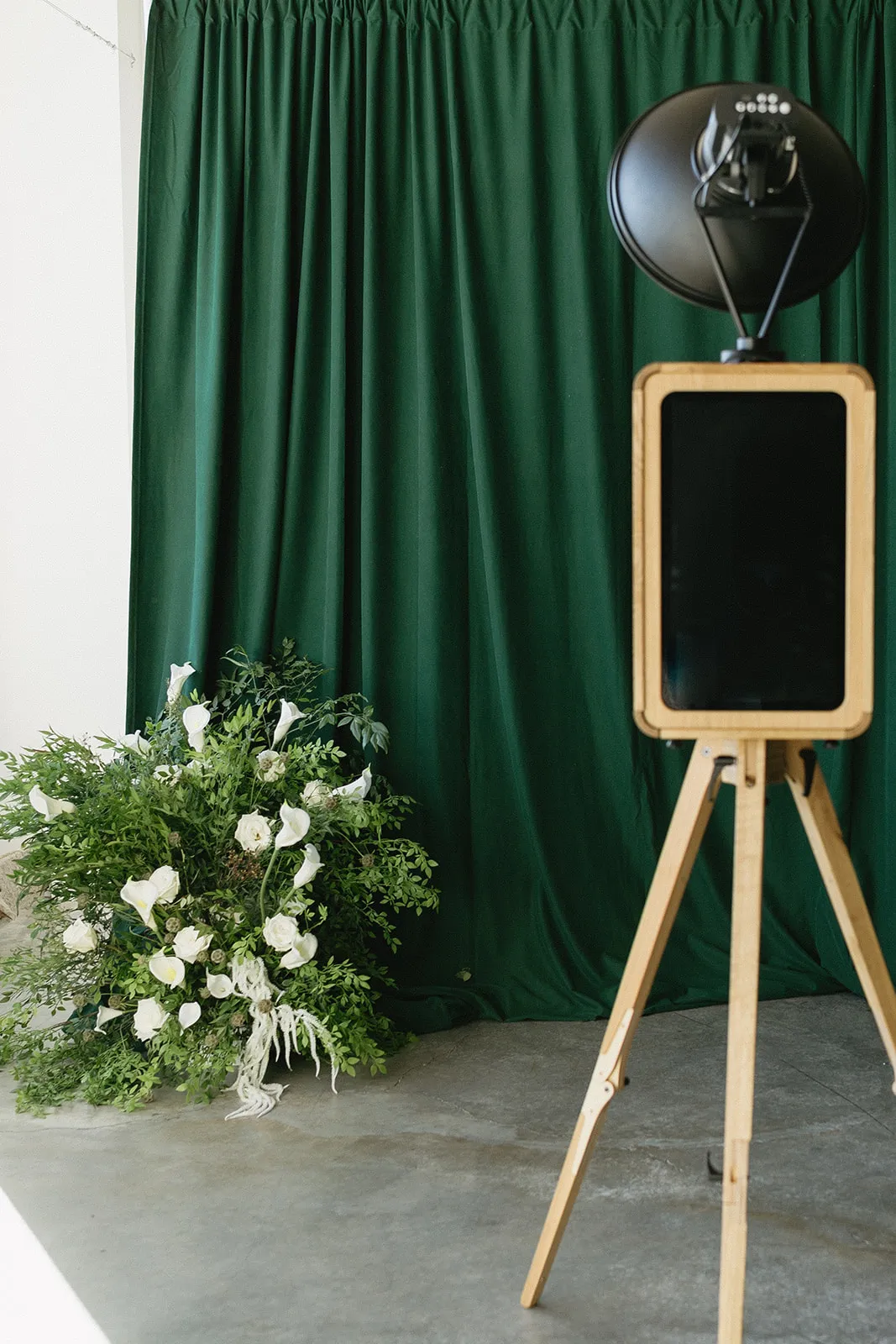 Oak ICON photo booth beside white wedding flowers and a green velvet backdrop