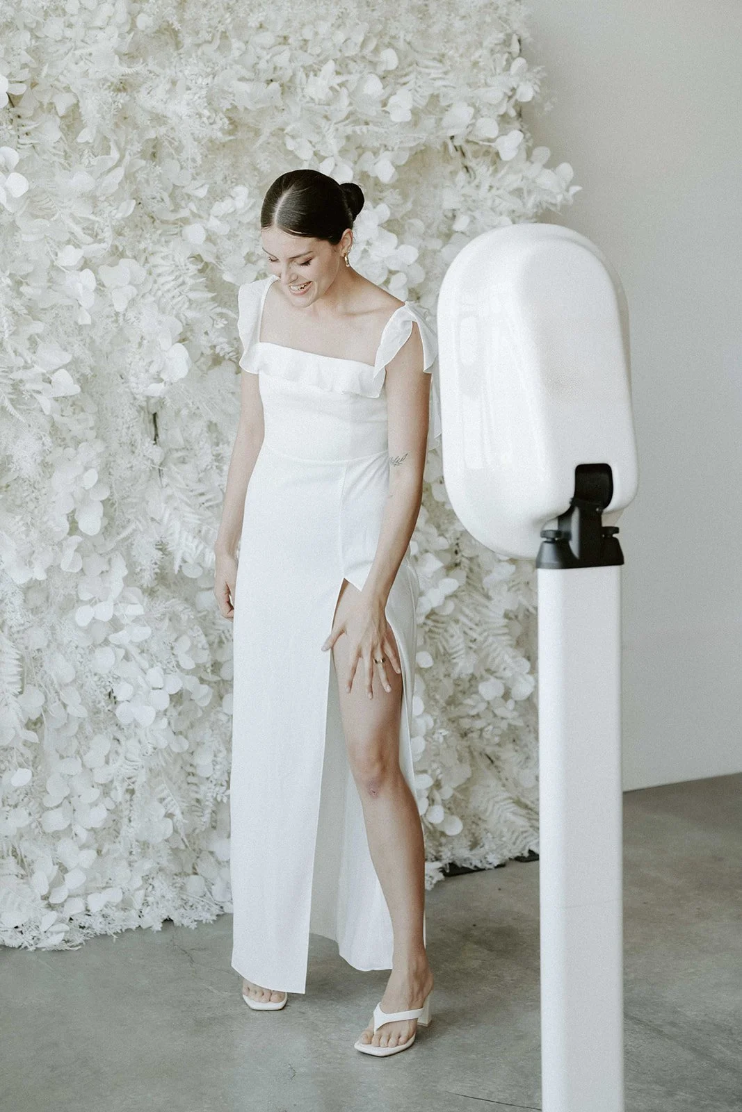 Bride posing at the Halo booth in front of a white floral wall
