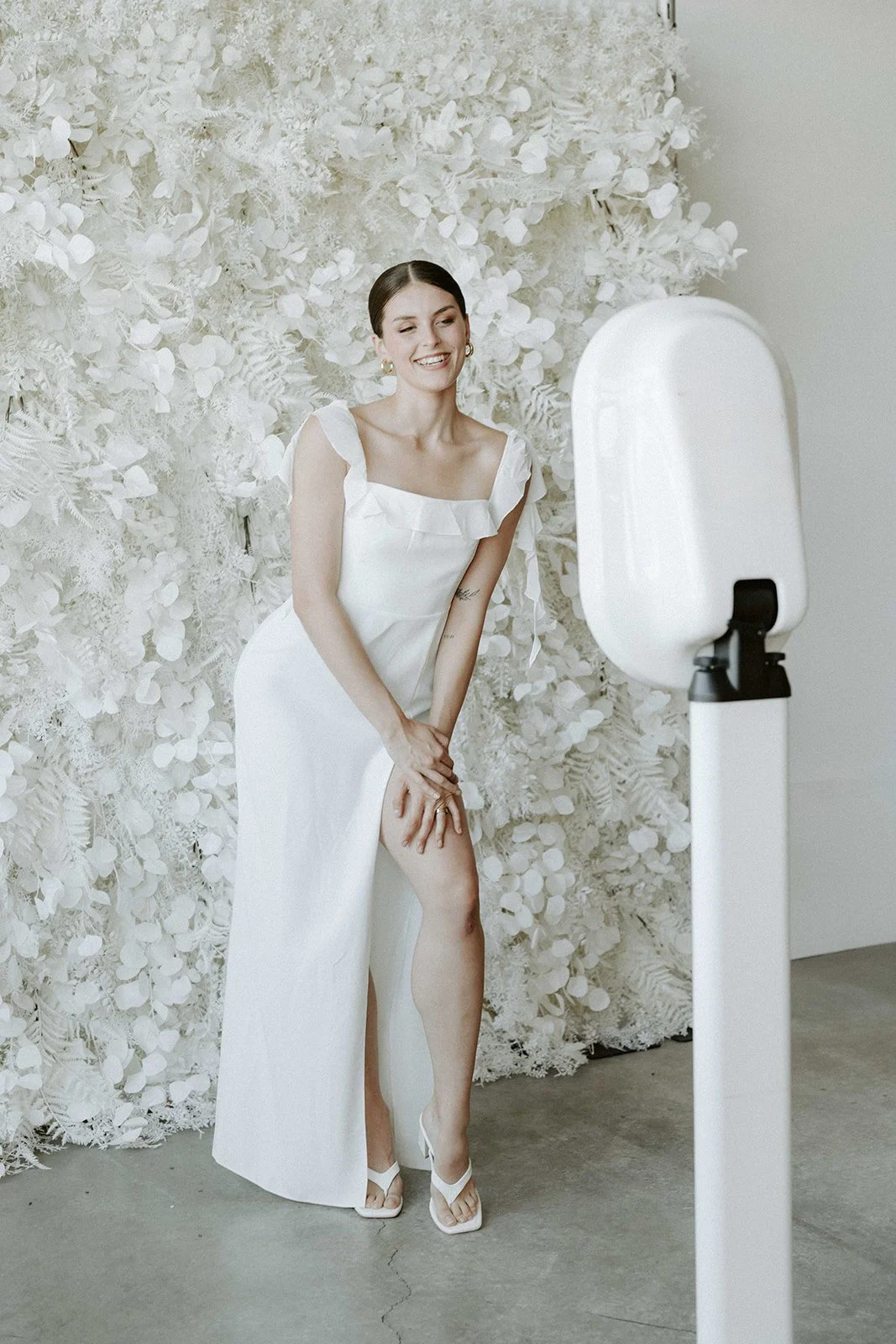 Bride posing in front of a floral backdrop with the Halo booth