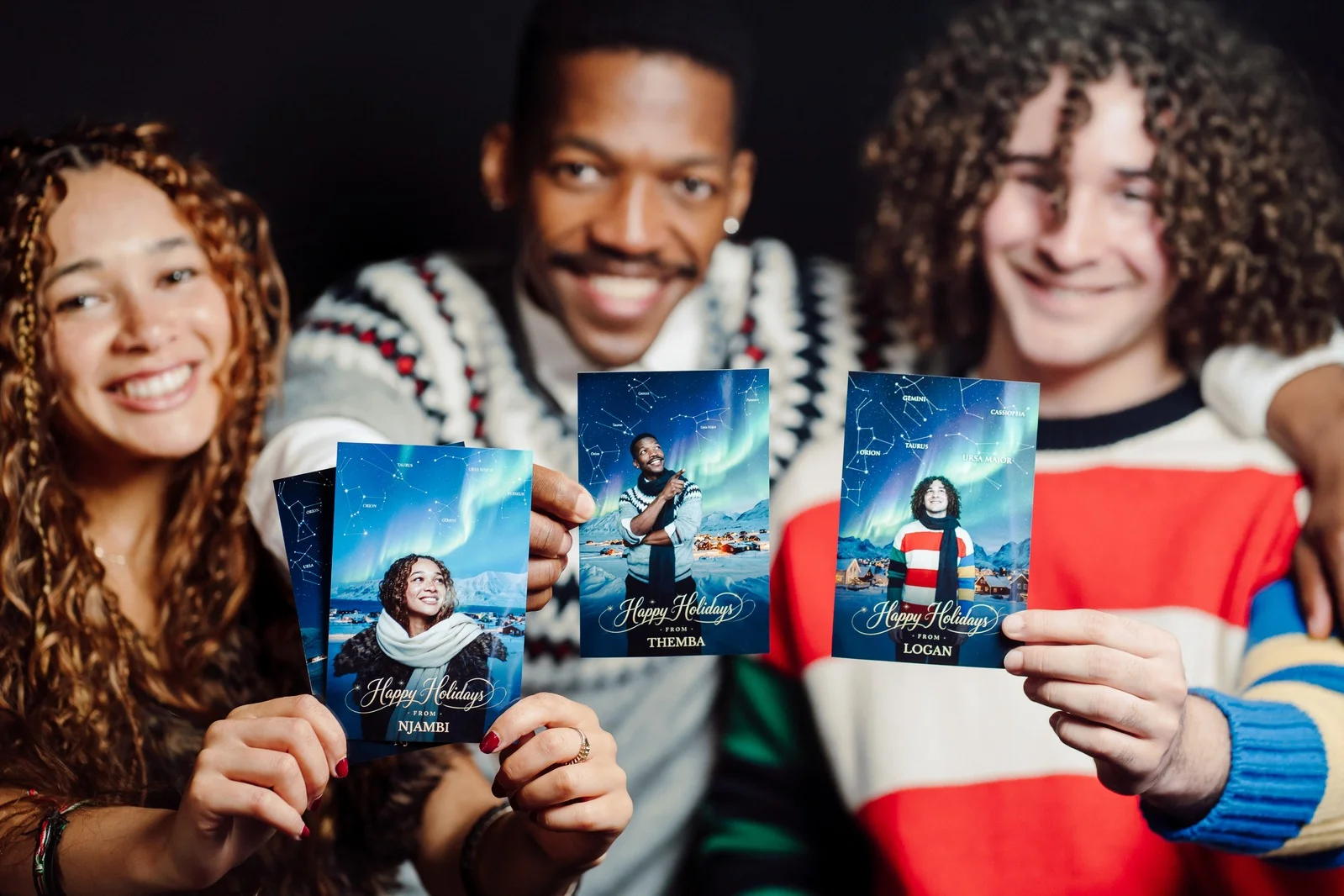 Friends holding personalised Holiday Constellation photo cards from a Christmas photo booth