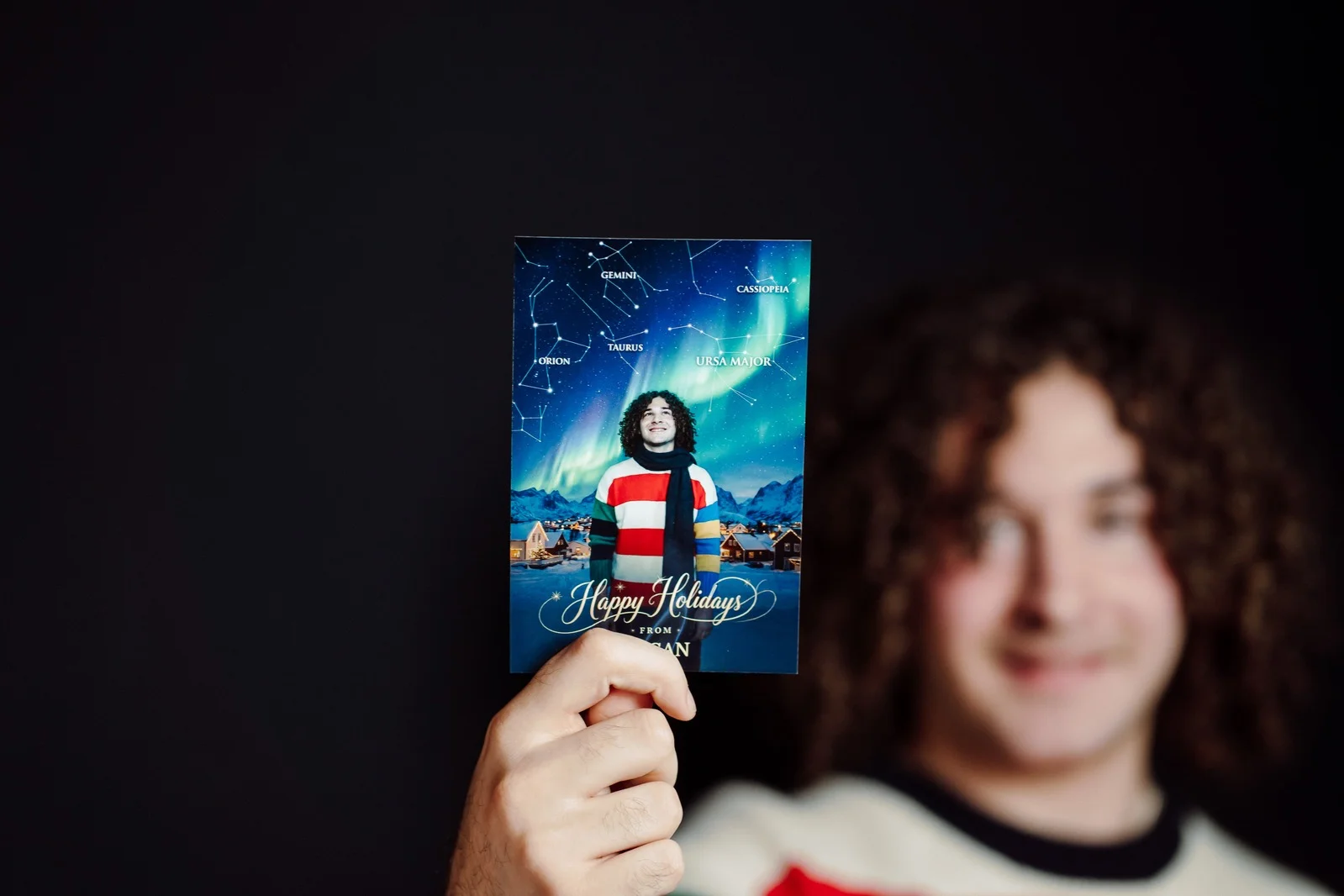 Guest holding a printed Holiday Constellation portrait with northern lights artwork