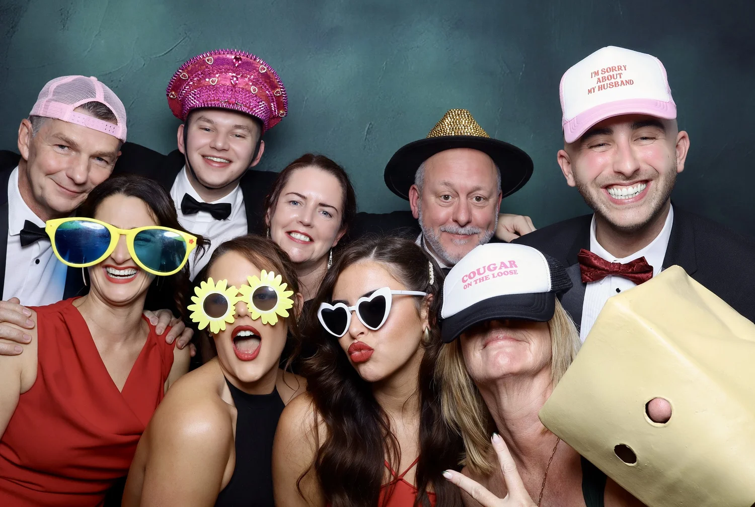 People wearing colorful and playful costumes and accessories, celebrating together in a photo booth.