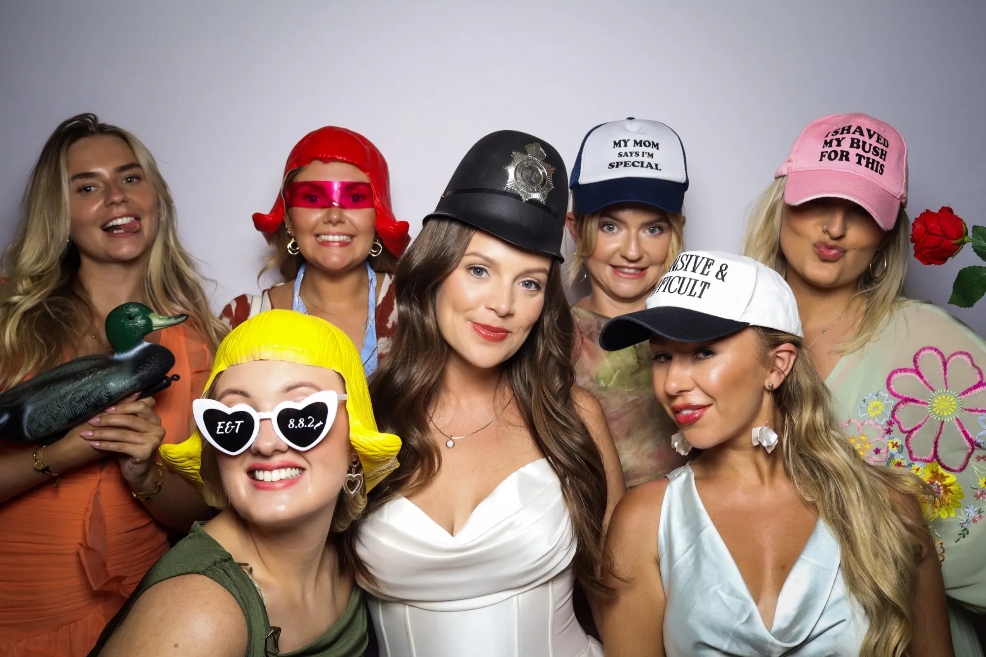 Bride and her friends in novelty hats and heart sunglasses posing in the Retro photo booth