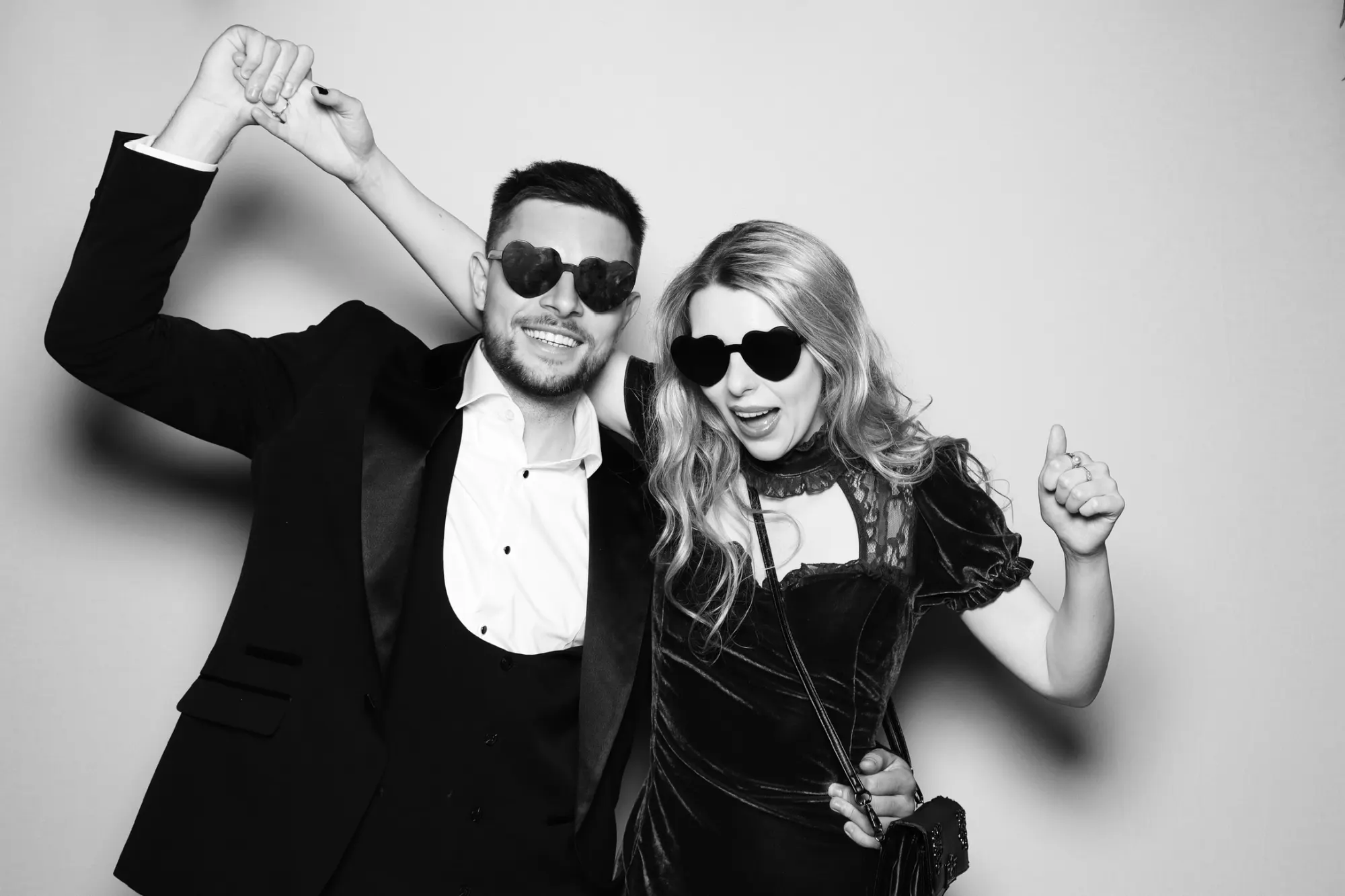 Wedding guests dancing in heart sunglasses in a black and white photo booth picture