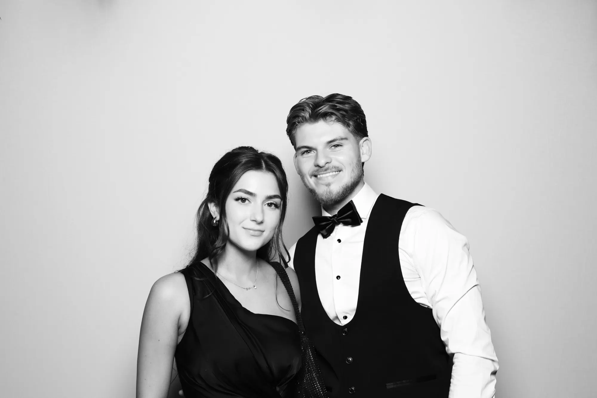 Wedding guests in a bow tie posing in a black and white photo booth picture