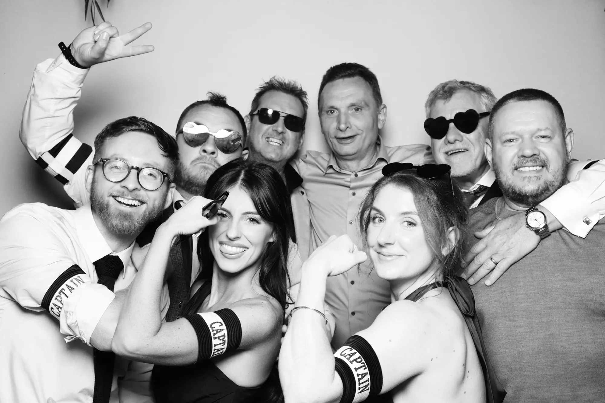 Group of wedding guests posing together in a black and white photo booth picture