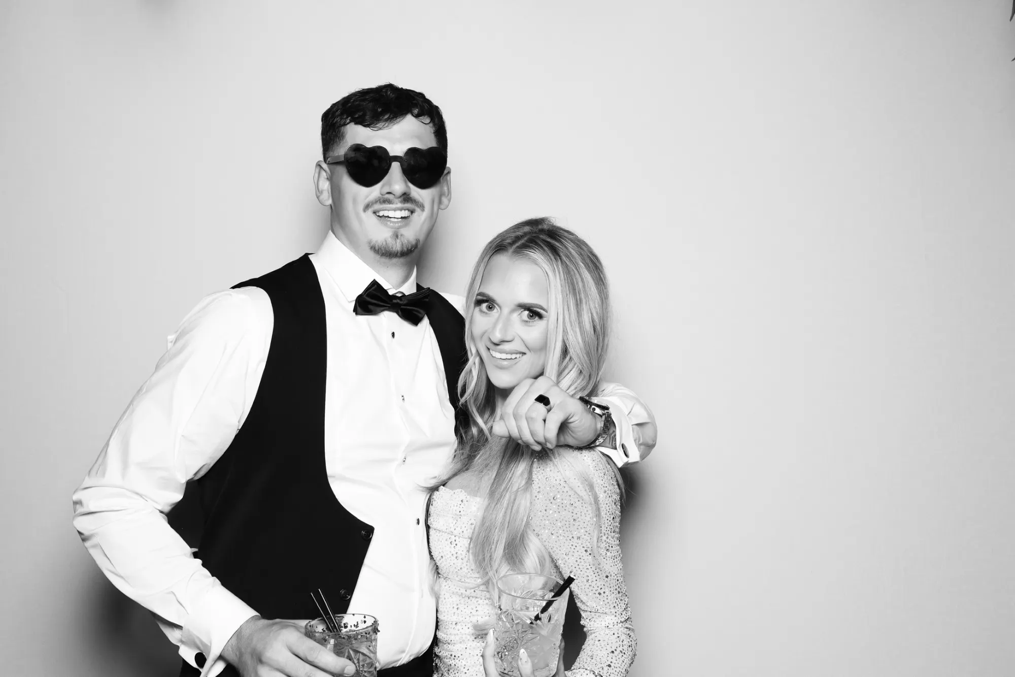 Couple with drinks and heart glasses in a black and white wedding photo booth picture