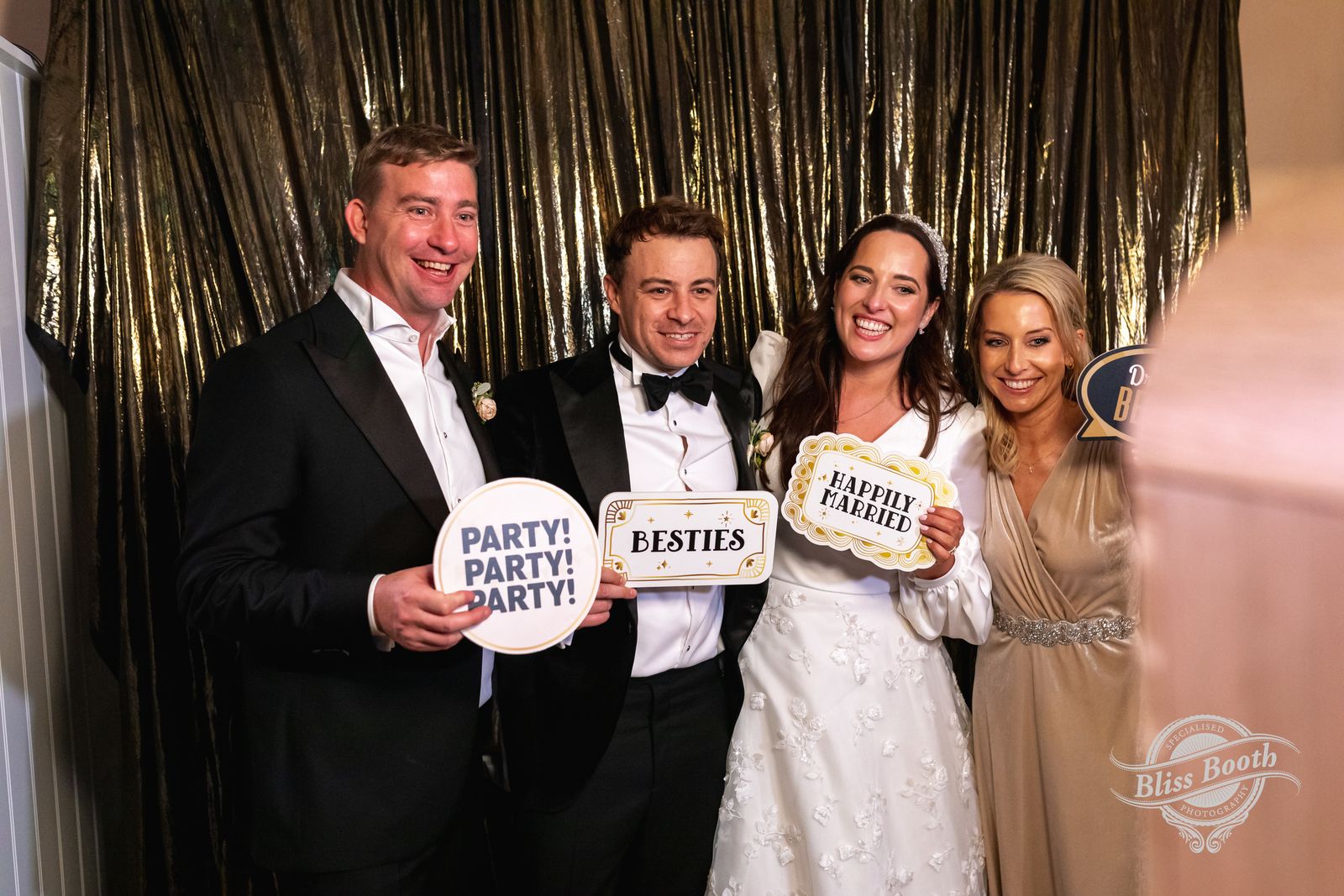 Wedding guests in black tie holding signs at the Retro photo booth