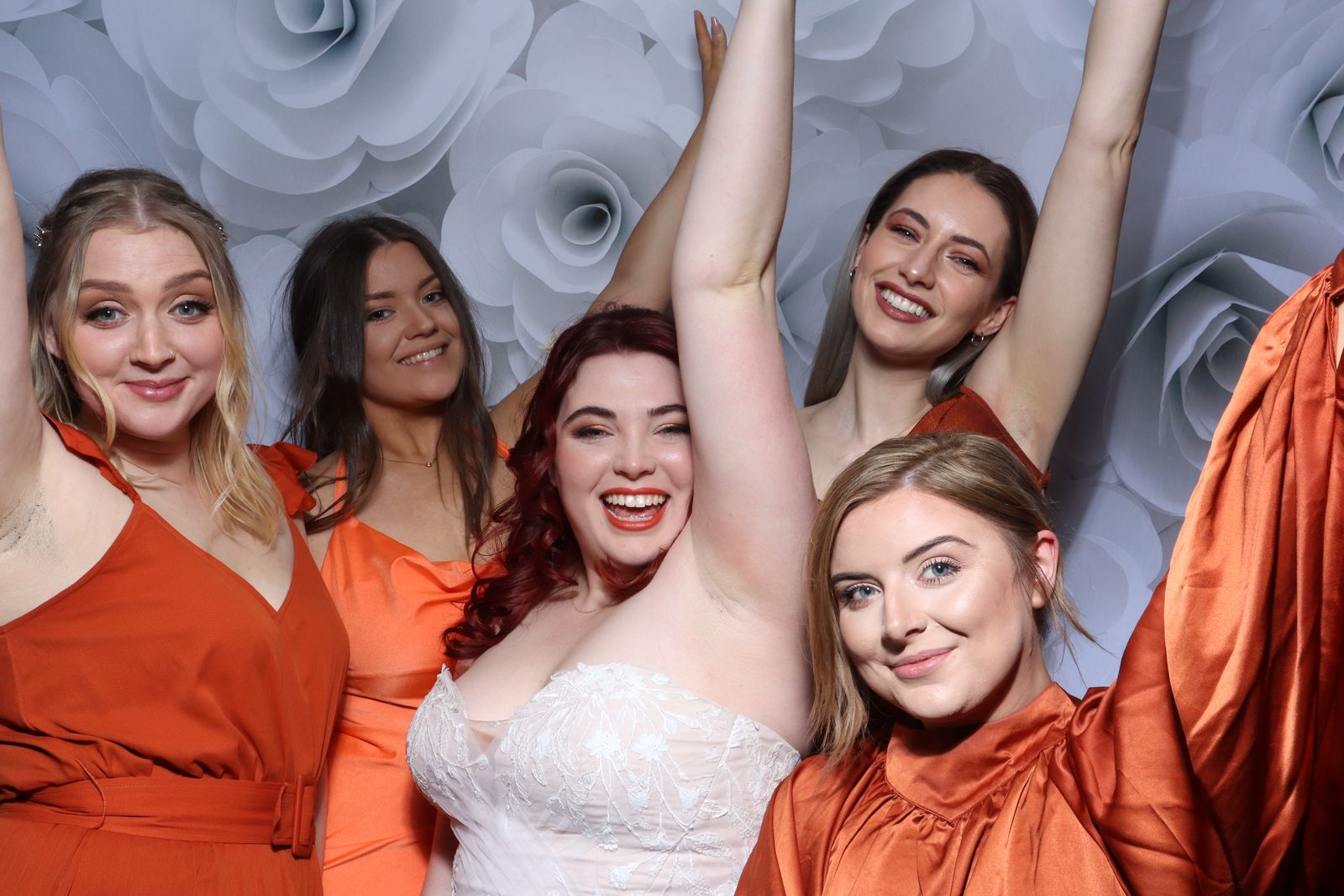 Bride and bridesmaids in burnt orange cheering in the Retro photo booth at a wedding