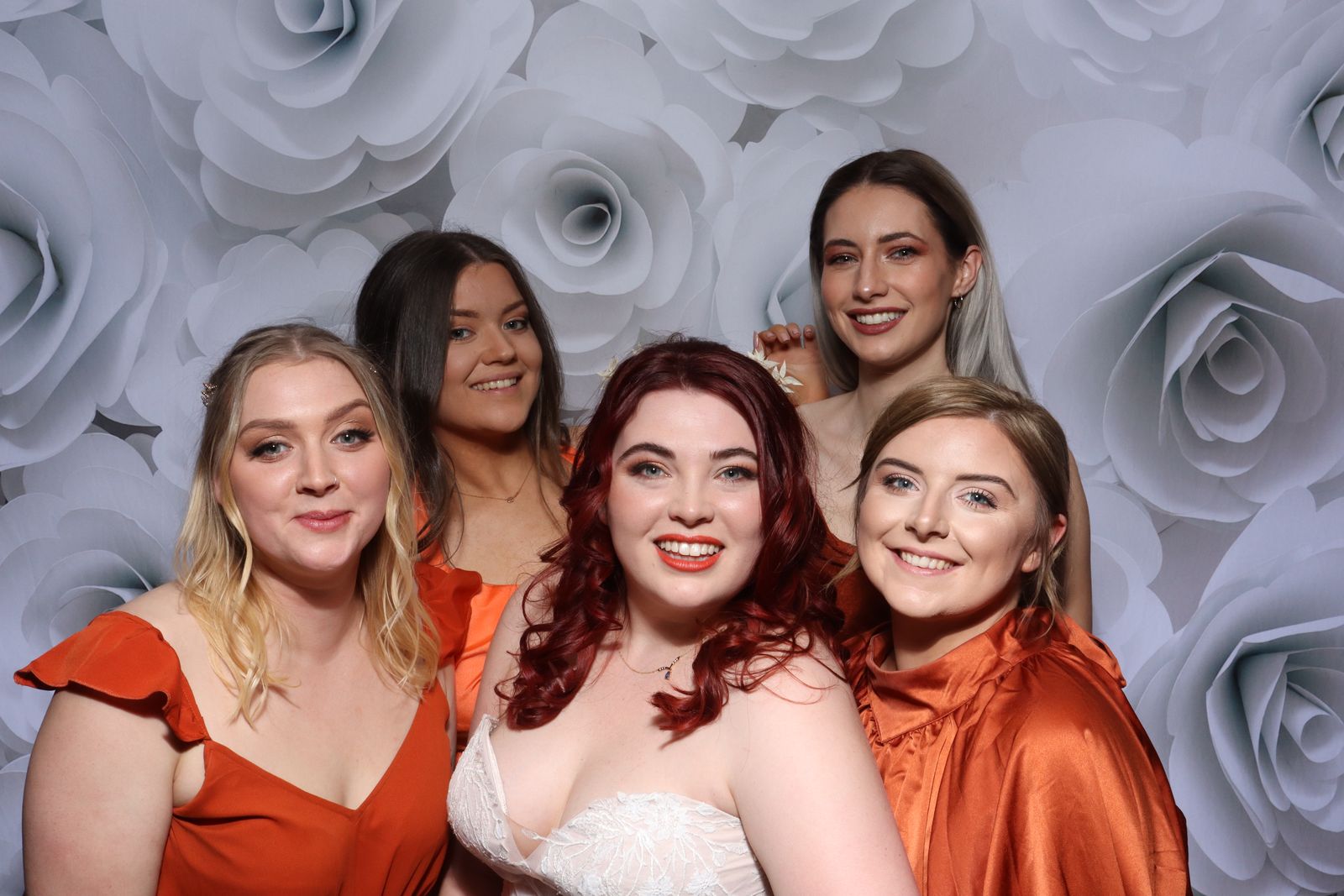 Bride with her bridesmaids against a white rose backdrop in the Retro photo booth