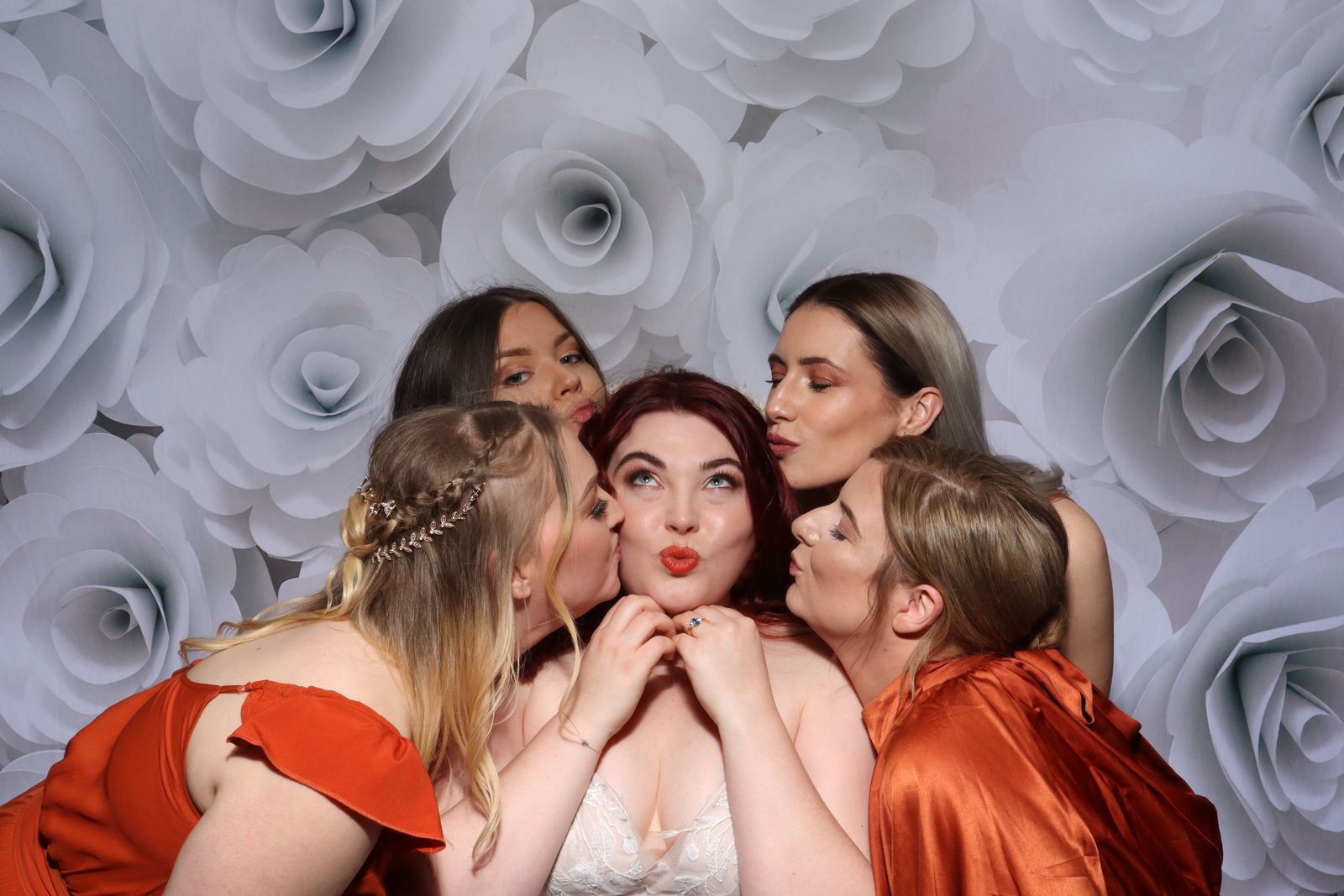 Bridesmaids kissing the bride on the cheek in the Retro photo booth