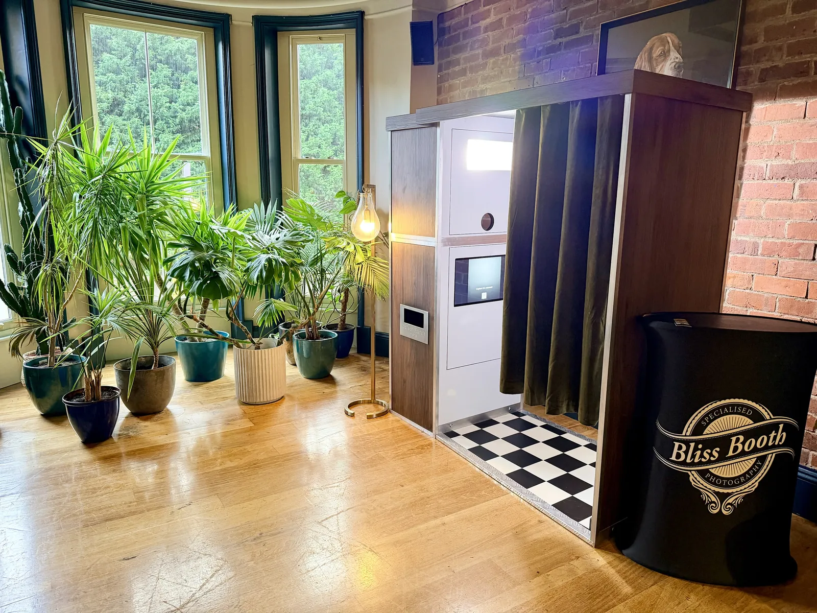 Photomatic vintage photo booth hire by Bliss Booth, set up in a bright venue room with plants and a floor lamp