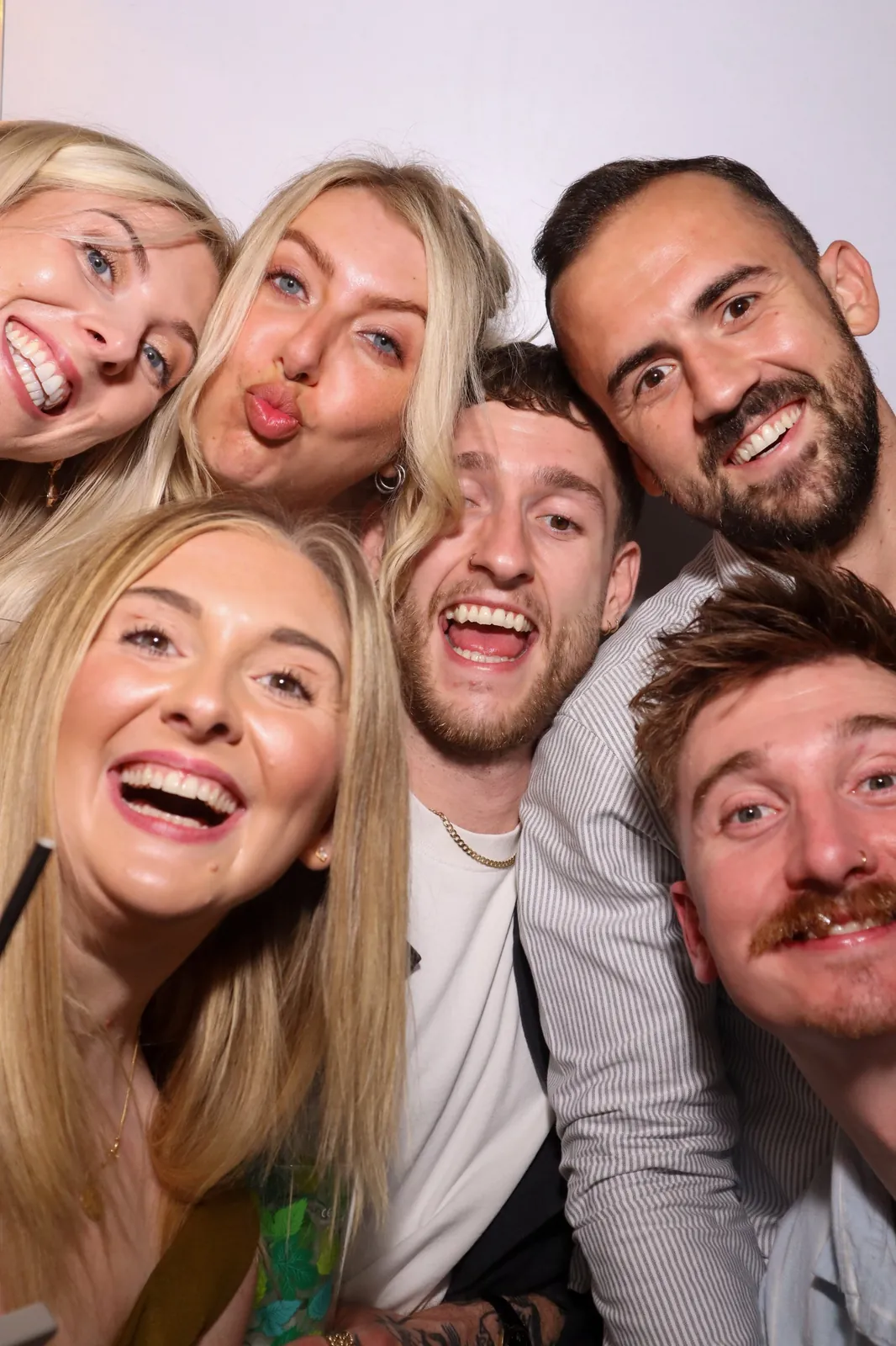 Group of friends laughing together inside the Photomatic photo booth