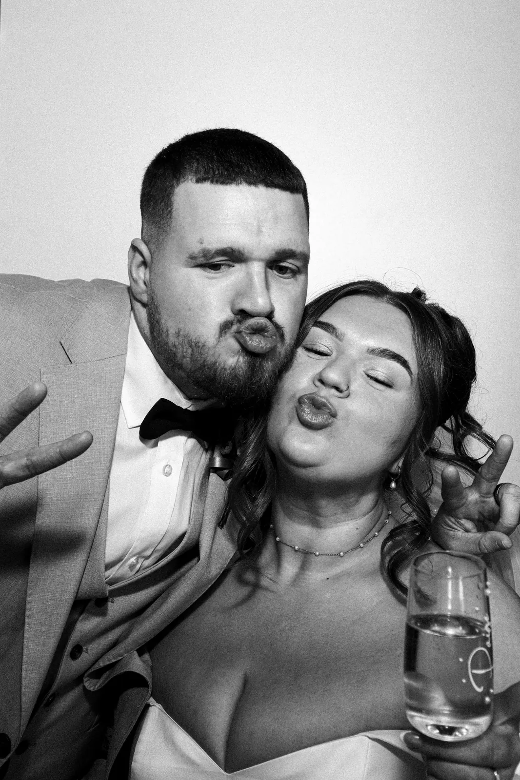 Bride and groom pulling kissy faces in the Photomatic photo booth, black and white