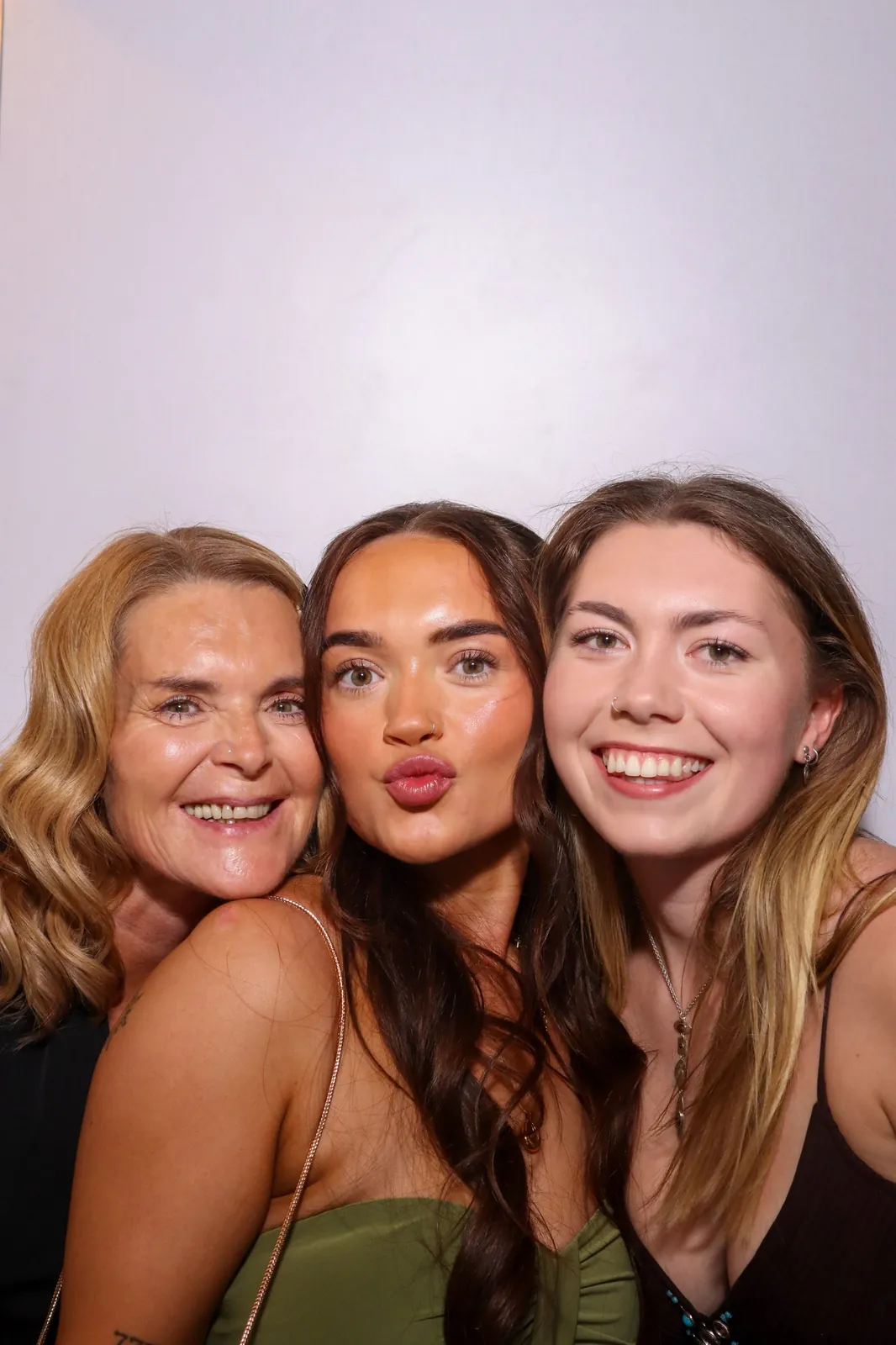 Three wedding guests smiling and pouting in the Photomatic photo booth