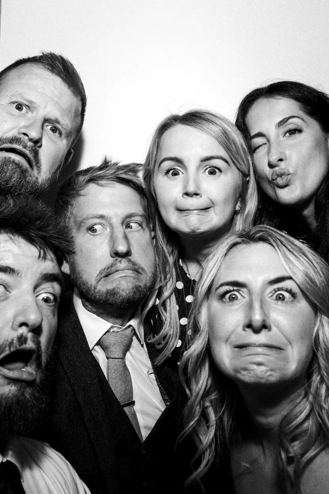 Wedding guests pulling funny faces in the Photomatic booth, black and white