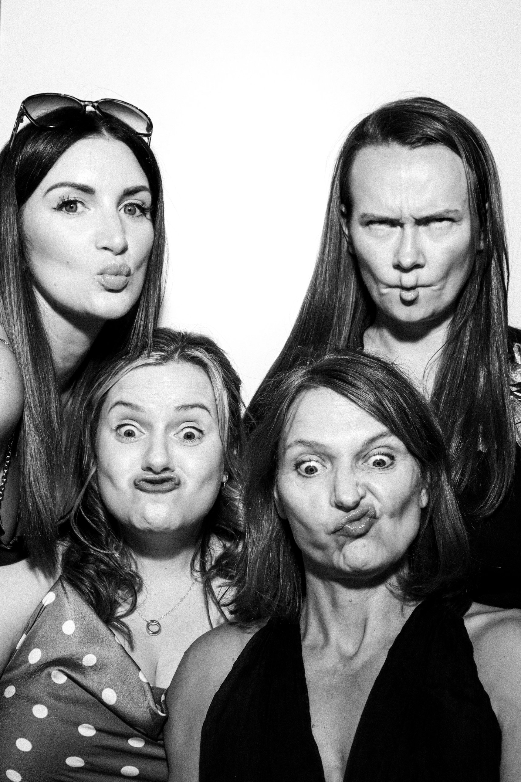 Four wedding guests pulling funny faces in black and white in the Photomatic