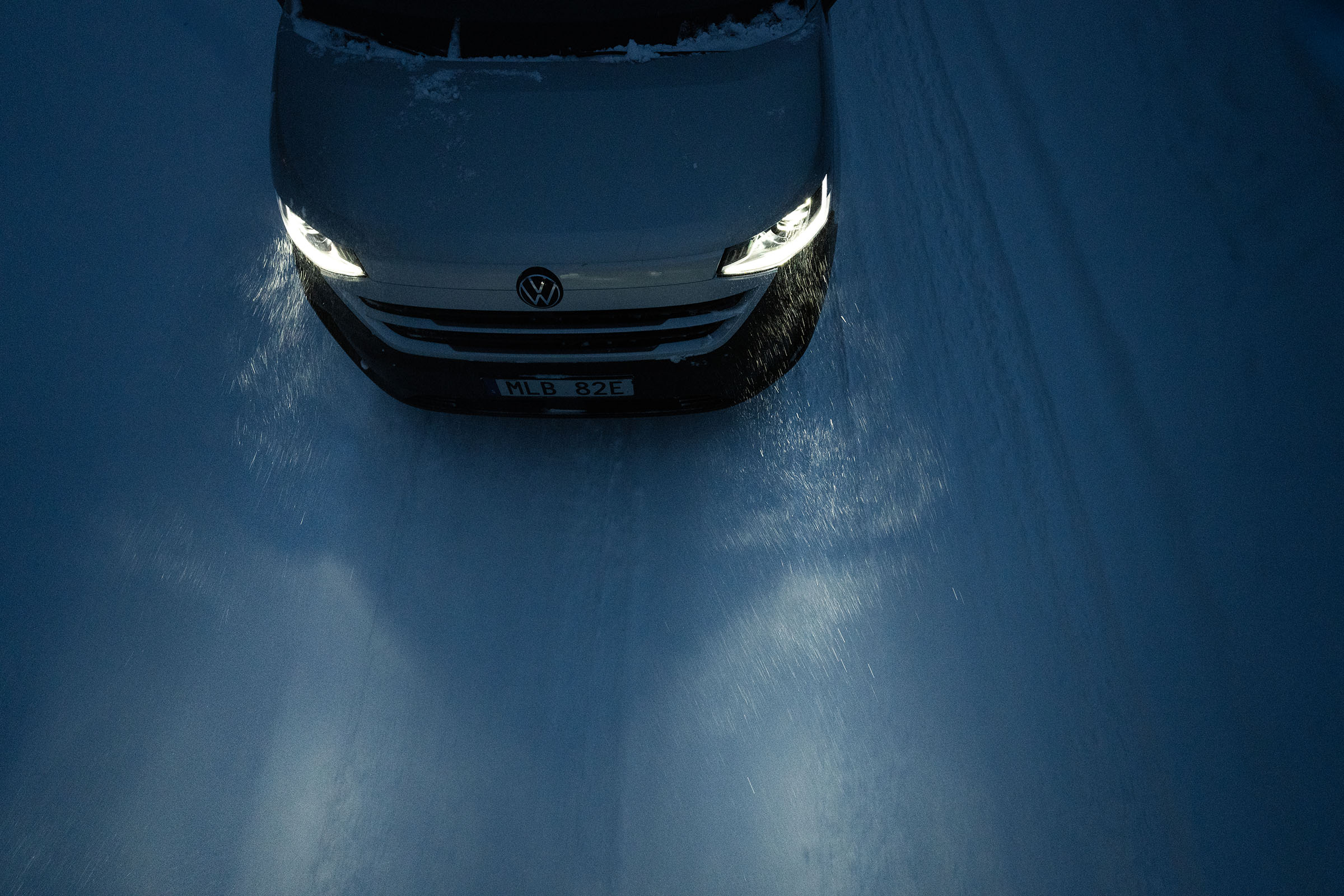 Bil med tända strålkastare i snö